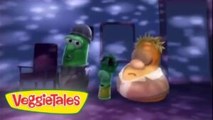 Screenshot from VeggieTales showing two anthropomorphic vegetables on a purple-lit stage with the VeggieTales logo in the corner.