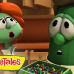 Two VeggieTales characters, a surprised tomato and a green pea, stand in a kitchen looking startled, with a bowl of colorful candies and the VeggieTales logo visible.