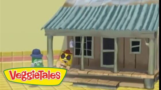 VeggieTales animation: a small brown house with a blue-green metal roof on a yellow street, two veggie characters stand in front (green cucumber with a blue hat and yellow character with sunglasses).