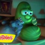 Green cucumber character from VeggieTales standing in a living room with a blue vegetable beside him; VeggieTales logo appears in the bottom-left corner.