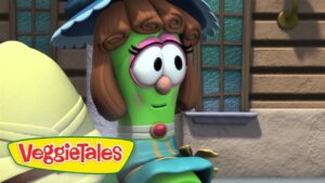 Cartoon green vegetable with brown curled hair and pink glasses stands outside a building; VeggieTales logo in the corner.