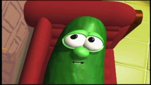 Green pickle character with large eyes and a small smile, lounging on a red couch in a bright room.