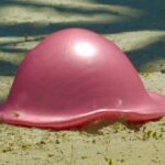 Pink inflatable beach toy shaped like a jellyfish resting on sandy ground at the beach
