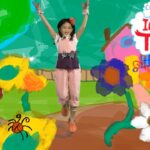 Young girl in pink jumpsuit jumps with arms raised in a bright, cartoon garden scene with colorful flowers and the words 'Can you imagine that!'.] ,
