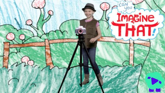 Girl posing with a camera on a tripod in front of a colorful drawn backdrop that says 'Imagine That!' in a playful scene.