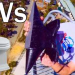 Thumbnail showing a man in sunglasses on a ride holding a large black anchor-like object beside a white toilet with a bold 'VS' between them.