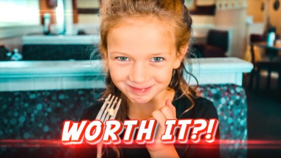 Smiling young girl holding a fork in a restaurant, with bold 'WORTH IT?!' text overlay.