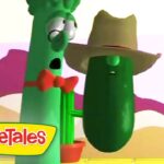 VeggieTales scene with a tall green cucumber in a red bow tie and a green pickle wearing a cowboy hat on a bright set.