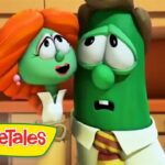 Two VeggieTales vegetables stand in a kitchen, looking up with surprised expressions; a yellow VeggieTales logo sits in the bottom-left corner.