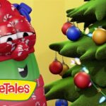 VeggieTales character with candy-cane wrap beside a decorated Christmas tree with colorful ornaments and lights, logo visible on the lower left.