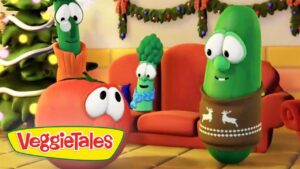 VeggieTales characters in a festively decorated living room with a Christmas tree; a cucumber in a reindeer sweater chats with an orange tomato.
