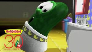 Green VeggieTales cucumber character leaning toward a kitchen counter, with a VeggieTales 30th Anniversary logo in the corner.