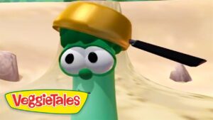 Larry the Cucumber from VeggieTales wearing a gold helmet in a desert setting.