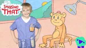 A smiling child in purple scrubs with pockets stands beside a cartoon monkey on a pink wall, with the 'Imagine That!' logo in a cloud on the left.