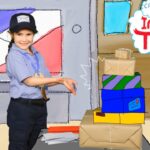 Smiling child in a blue uniform and cap stands beside a stack of wrapped gift boxes in a cartoon-style room with an 'Imagine That!' sign.