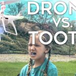 Thumbnail for a video showing a white quadcopter flying near a girl in a park while a man with a controller watches, overlaid with the text 'DRONE VS. TOOTH'