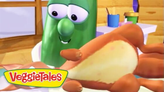 Green cucumber character from VeggieTales smiling as a hand holds a bread bun in a kitchen setting.