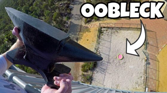 Person on a tall structure holds a large black anchor-like tool over the edge, with a fenced gravel area and a pink-green ball below; a bold 'OBLECK' thumbnail label is visible ahead of the scene.