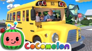 Yellow school bus with a cheerful driver and children looking out the windows on a sunny street, Cocomelon logo in the corner.