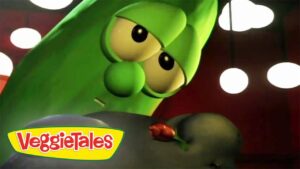 Close-up of a green VeggieTales cucumber character with big eyes, logo in the bottom-left corner.