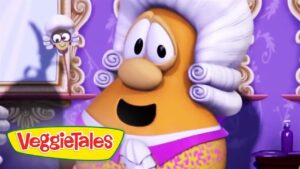 Animated carrot character with a white powdered wig and purple outfit, in a VeggieTales scene with the logo visible at the bottom left.