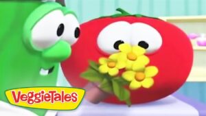 Green VeggieTales cucumber embraces a red tomato holding a bouquet of yellow flowers.