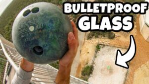 Thumbnail: person on a balcony pressing a bowling ball against a glass panel, implying a bulletproof glass test, with bold 'BULLETPROOF GLASS' text in the corner.