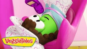 Green VeggieTales character sleeping in a pink chair, wrapped in a white blanket with pink hearts; VeggieTales logo bottom left.