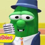 Green VeggieTales character wearing a blue fedora and suit, singing into a vintage microphone with the VeggieTales logo in the corner.