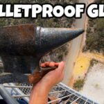 Person on a high balcony grips a heavy metal anvil with a view of ground far below; thumbnail reads 'BULLETPROOF GLASS'.
