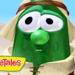 Animated green cucumber character in desert robes with a surprised expression; VeggieTales logo in the corner.