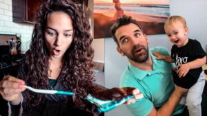 Woman with curly hair looks surprised while holding a turquoise item toward the camera; a man holds a smiling baby beside her in a kitchen/dining area.