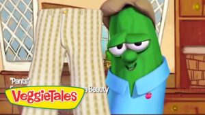 Green VeggieTales character in a blue shirt and brown hat looks at a tall pair of striped pants in a cozy kitchen; VeggieTales logo is visible in the corner.