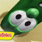 Close-up of a green cucumber cartoon head with big eyes from VeggieTales, with the VeggieTales logo in the corner.