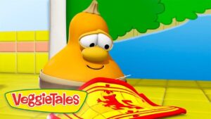 Cartoon yellow veggie character from VeggieTales smiles at a red-and-yellow banner or cape on a bright tiled floor, with the VeggieTales logo in the corner.