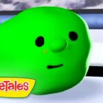 Close-up of a bright green cucumber character with black eyes and a small mouth, from VeggieTales, resting on a white surface with a logo in the corner.