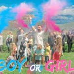 Outdoor gender reveal celebration with a crowd cheering as blue and pink powder bursts, and the bold 'BOY OR GIRL' text at the bottom.