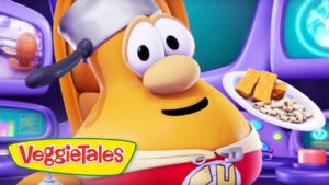 Orange VeggieTales character wearing a white headband in a purple spaceship cockpit, holding a plate of pasta and crackers.