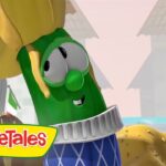Larry the cucumber from VeggieTales wearing a blue patterned sweater and a yellow hat, smiling at the camera.