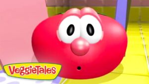 Red round cartoon character with big white eyes and surprised expression, VeggieTales logo in the bottom-left corner.