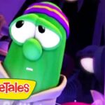 Green VeggieTales character with a striped purple-yellow hat in a purple-lit scene, VeggieTales logo at bottom left.