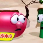 Pink VeggieTales character and green cucumber in a desert, wearing headbands, looking surprised at each other.