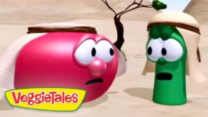 Pink VeggieTales character and green cucumber in a desert, wearing headbands, looking surprised at each other.