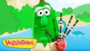Larry the Cucumber from VeggieTales holds a bagpipe by a river with green hills in the background.