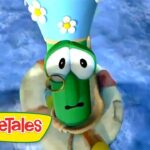 Green cucumber character from VeggieTales wearing a blue hat with daisies and a monocle against a blue background.