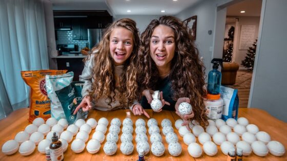 Two girls smiling at a kitchen table with rows of hollow eggshells, crafting speckled egg decorations.
