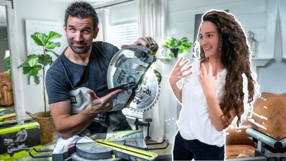 Man operating a circular saw while a woman nearby looks surprised and happy in a home workshop.