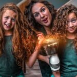 Three girls with long curly hair pose for a bad-vs-good hair demo: left labeled wrong, right labeled correct, with a central adult holding a prop device.