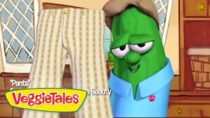 Green VeggieTales character in a blue shirt looks at a pair of striped pants labeled 'Pants' in a cozy kitchen scene.