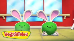Two green VeggieTales characters with large pink bunny ears stand in a bright room, smiling at the viewer, with small bunny friends nearby and the VeggieTales logo visible.